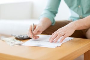 economia-financas-economia-e-conceito-de-casa-close-up-do-homem-com-calculadora-contando-dinheiro-e-fazendo-anotacoes-em-casa_380164-77895